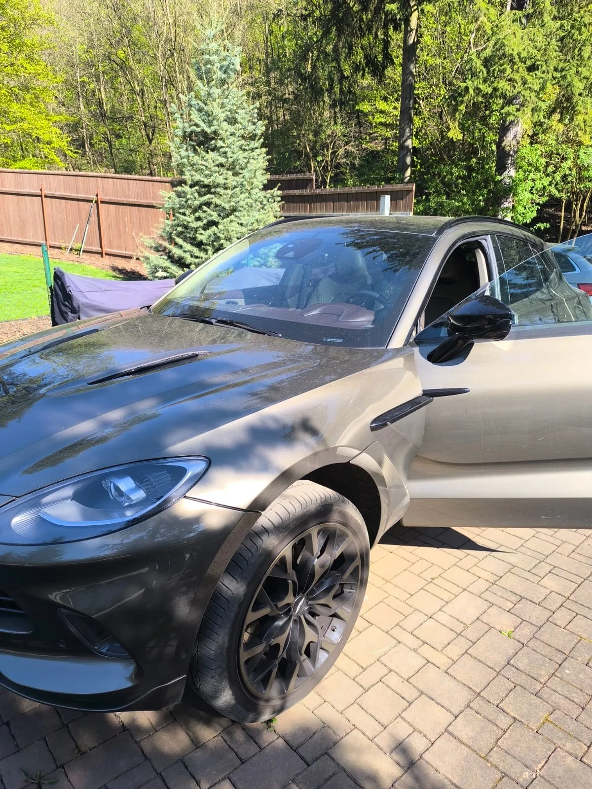 Aston Martin DBX zepředu s otevřenými dveřmi řidiče po nouzovém otevření auta v Praze